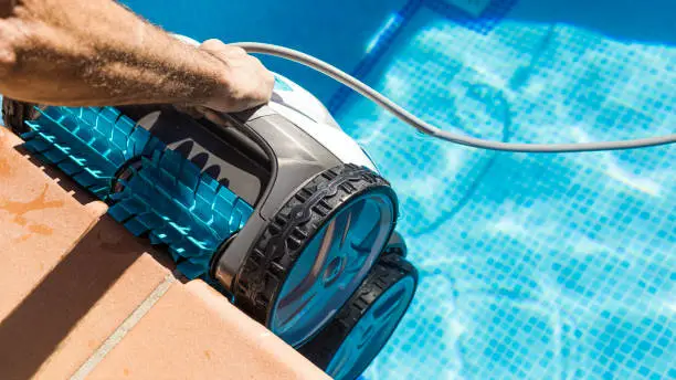 Pool specialist carefully treating heavy calcium scale along an elevated spa spillway