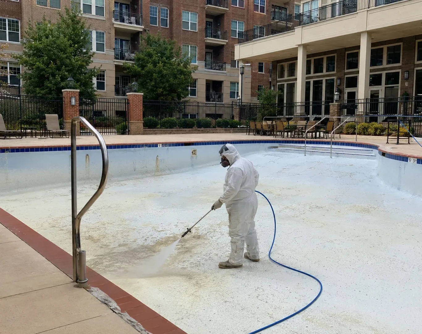 Technician acid washing stained backyard pool before summer use in Saugus